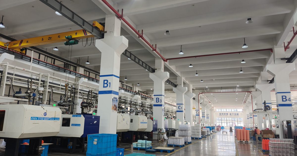 PET preform moulding hall, conveying lines above a full row of presses, each fitted with a MegaColor dosing machine